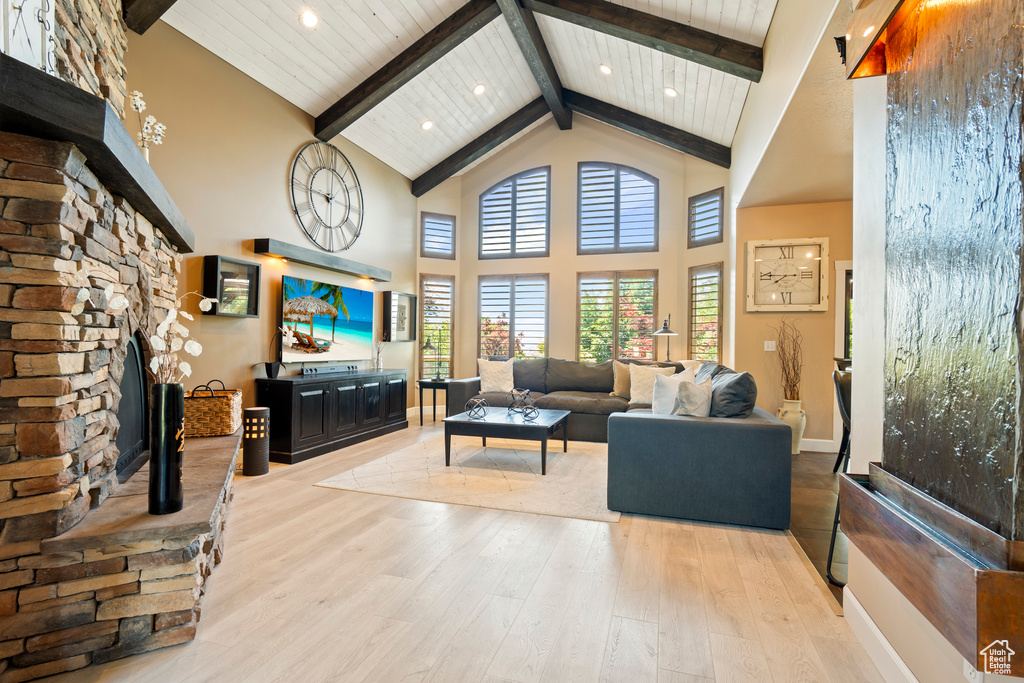 Living room with high vaulted ceiling, wood finished floors, beam ceiling, and recessed lighting