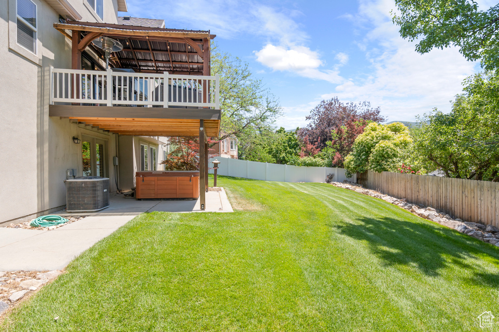 Fenced backyard with a hot tub, a patio, and a wooden deck