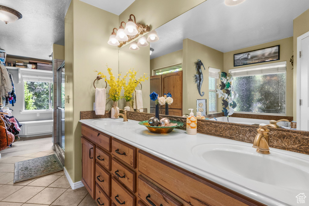 Bathroom featuring tile patterned floors, double vanity, a shower stall, and a garden tub