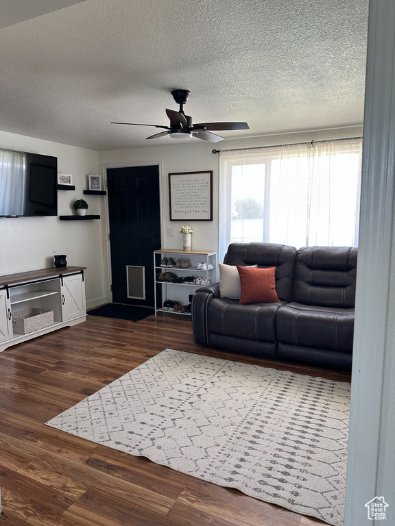 Living room featuring a textured ceiling, a ceiling fan, and dark wood-style flooring