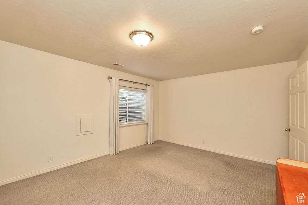 Unfurnished room with a smoke detector and light carpet