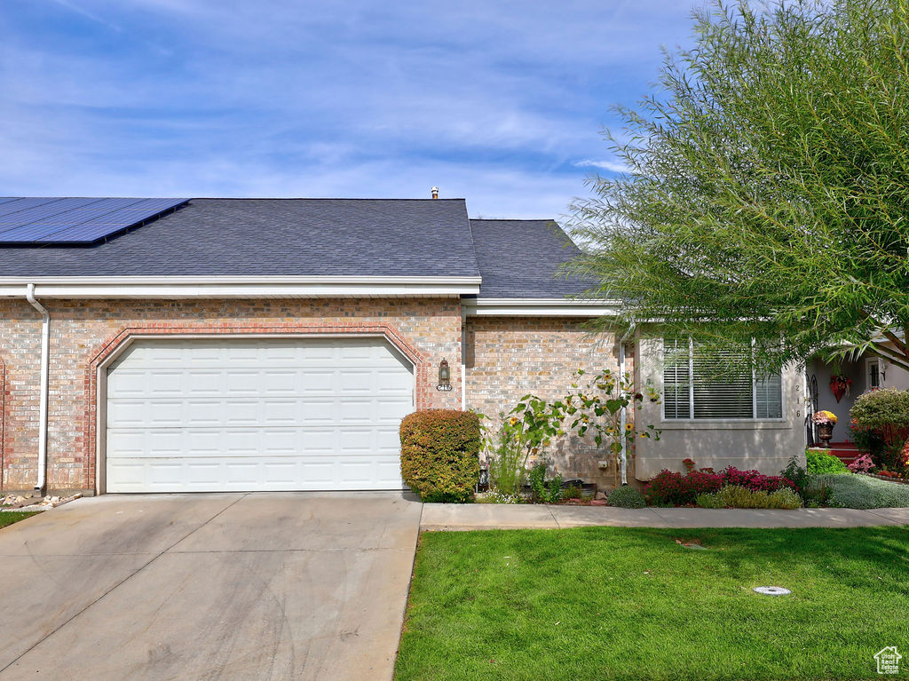 View of front facade featuring concrete driveway, a shingled roof, and brick siding