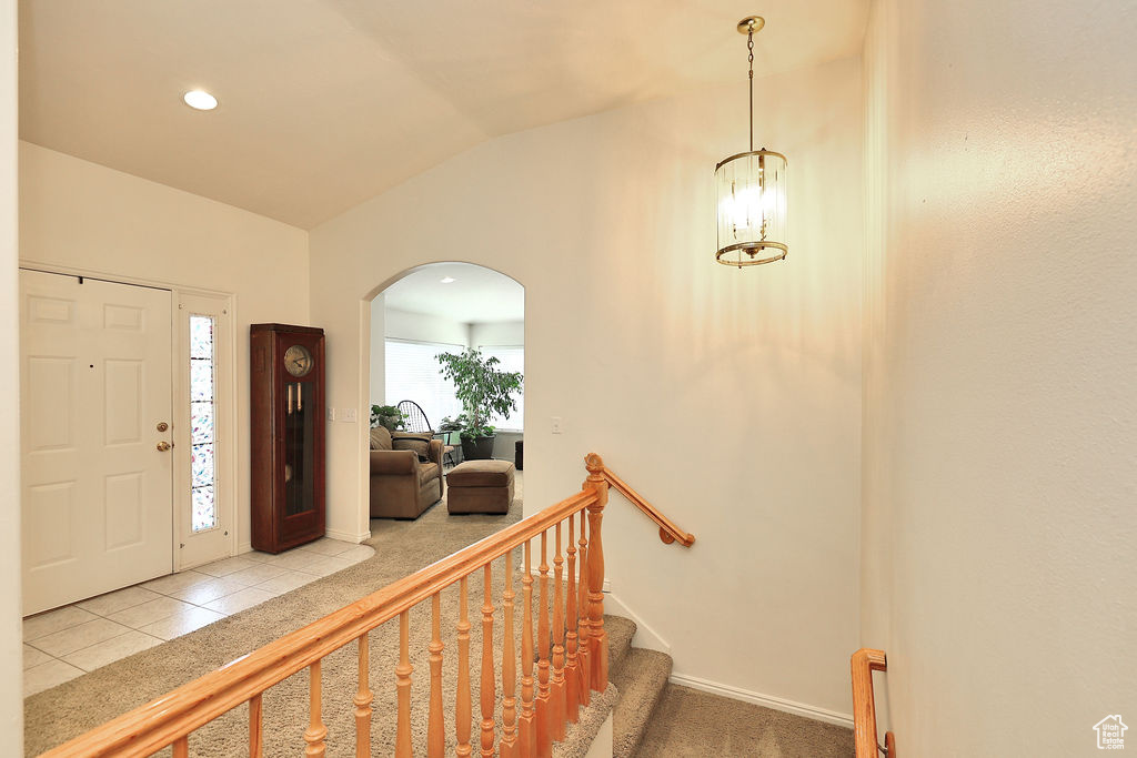 Entryway featuring arched walkways, lofted ceiling, light tile patterned flooring, a chandelier, and recessed lighting