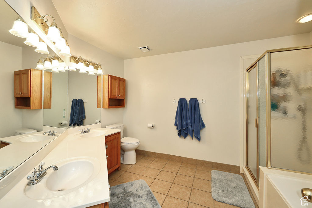 Bathroom featuring a stall shower, double vanity, tile patterned floors, and a bathtub