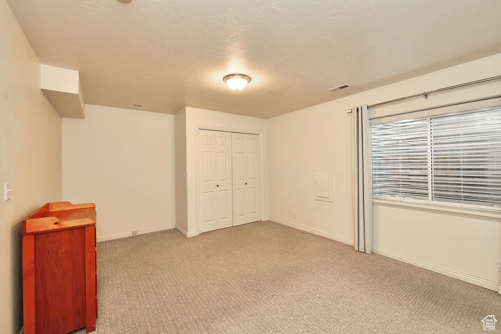 Unfurnished bedroom featuring light colored carpet and a closet