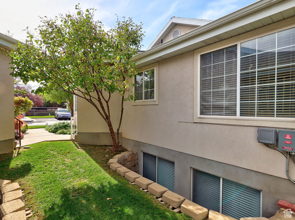 View of side of property featuring a yard and stucco siding