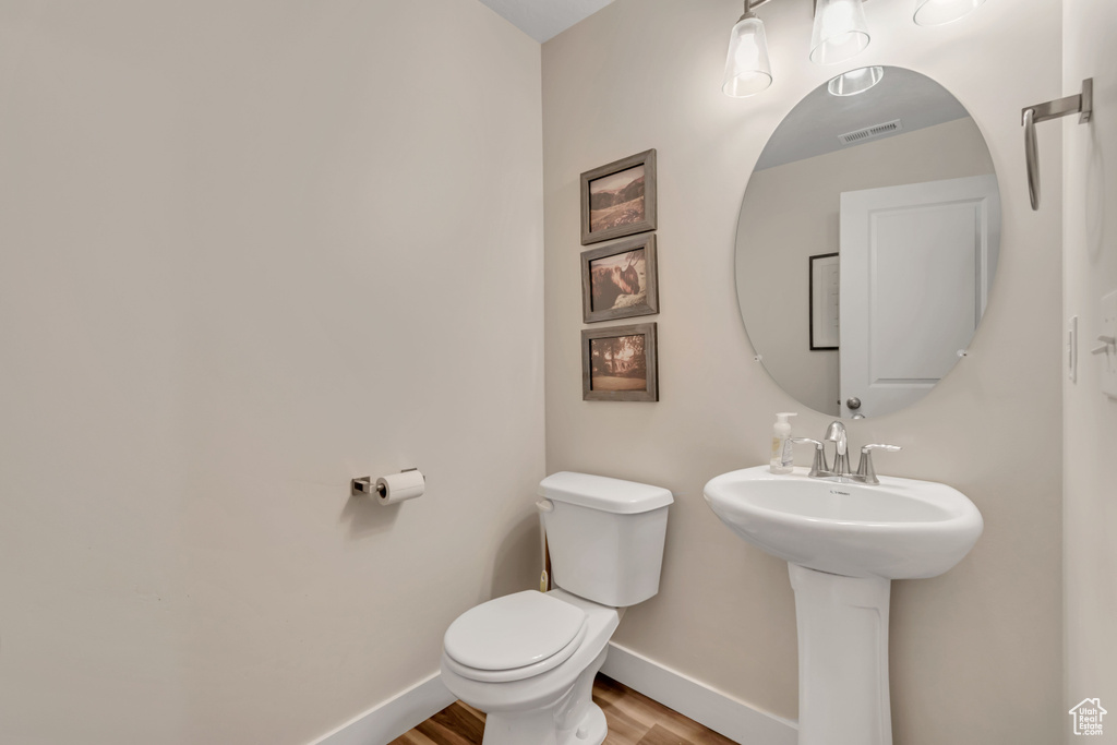 Half bath featuring toilet and wood finished floors