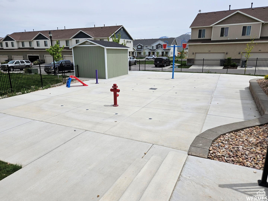 View of community with a residential view, a garage, concrete driveway, and a storage shed