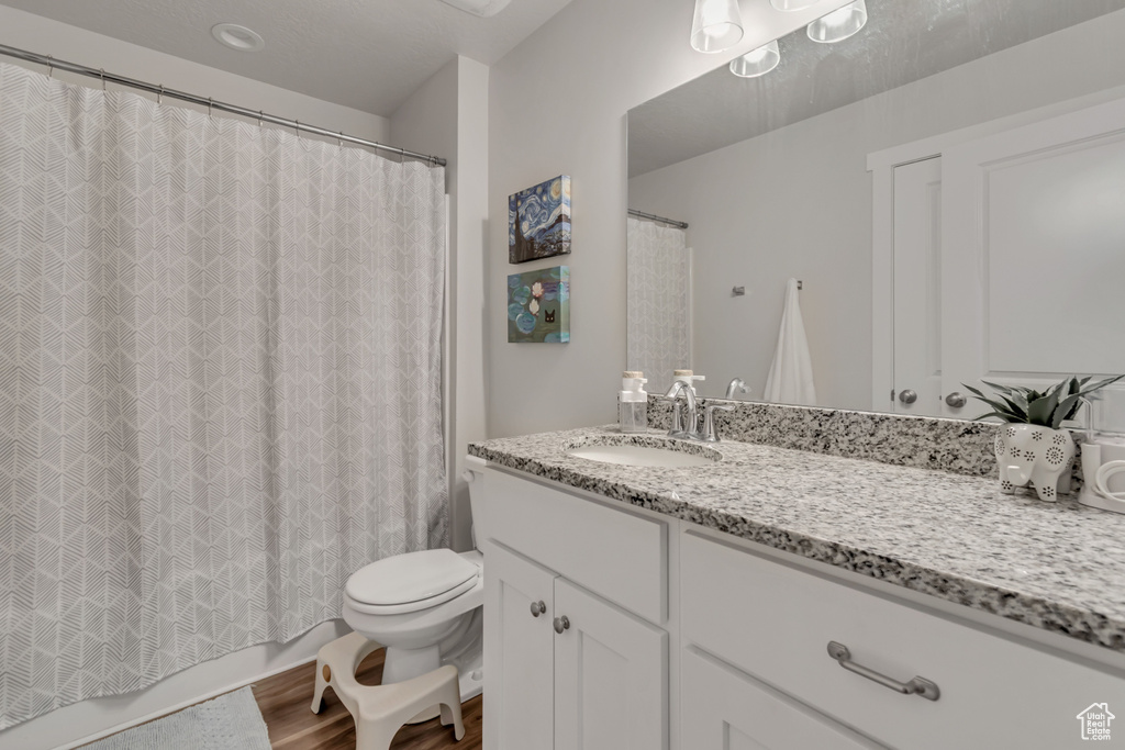 Bathroom featuring vanity, wood finished floors, and shower / bathtub combination with curtain