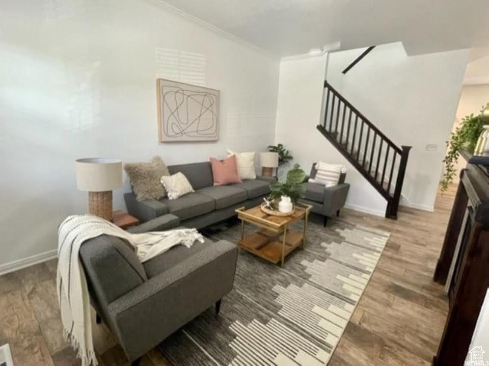 Living area featuring stairs, ornamental molding, and wood finished floors