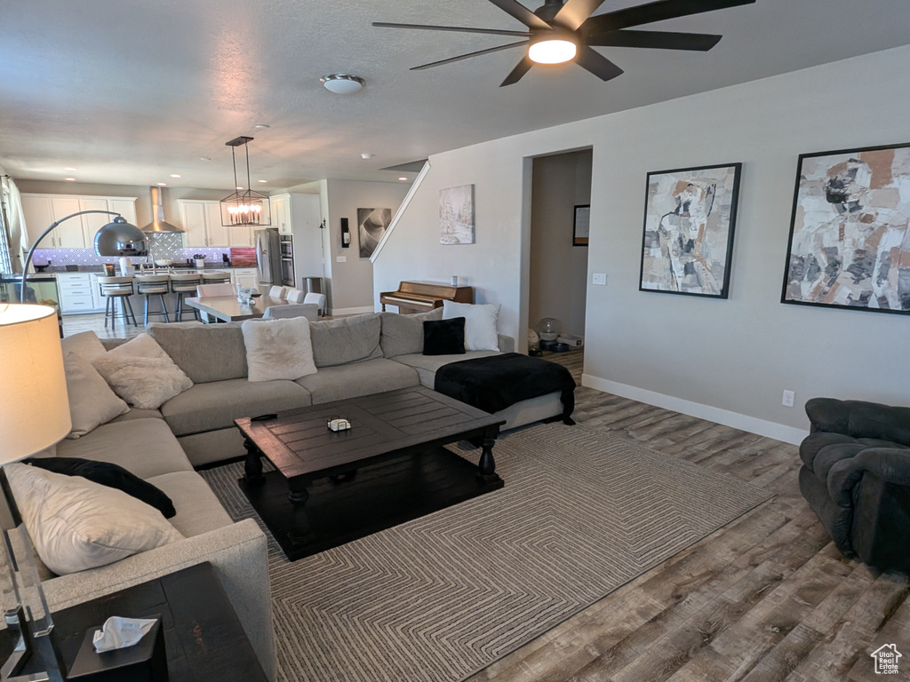 Living area featuring a ceiling fan, wood finished floors, and a chandelier