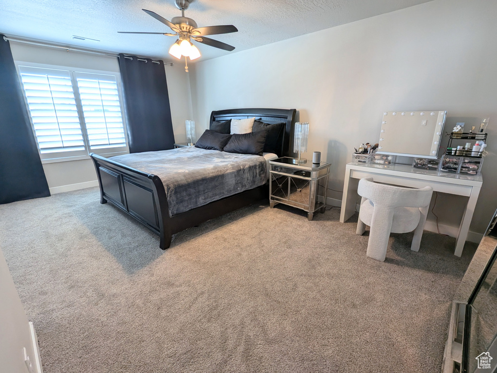 Bedroom featuring a textured ceiling, light colored carpet, and ceiling fan