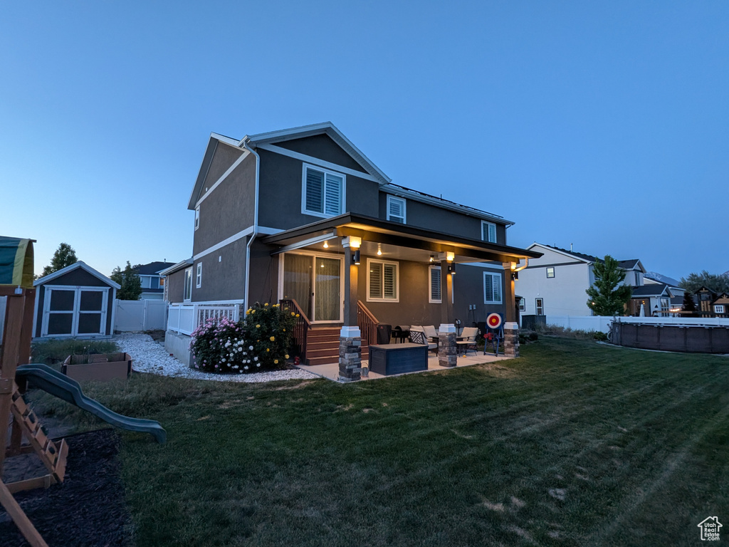Rear view of property with a storage unit, a fenced backyard, a patio, and stucco siding
