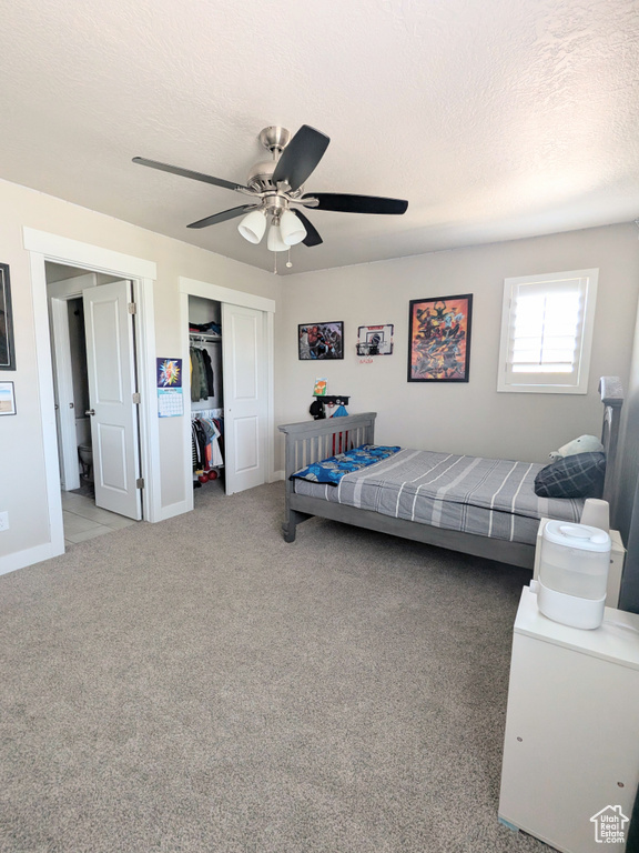 Bedroom with a textured ceiling, a closet, carpet floors, and a ceiling fan