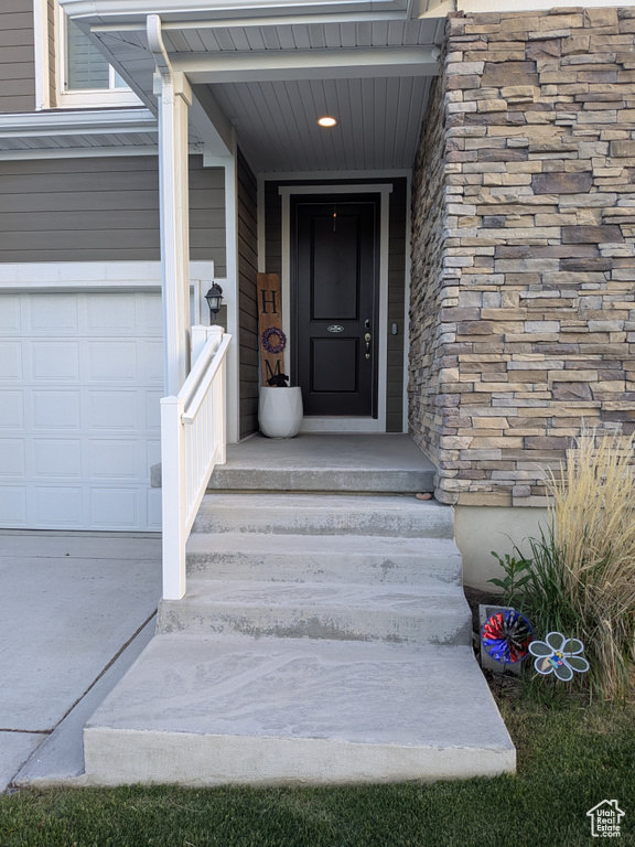 View of exterior entry featuring a garage and stone siding