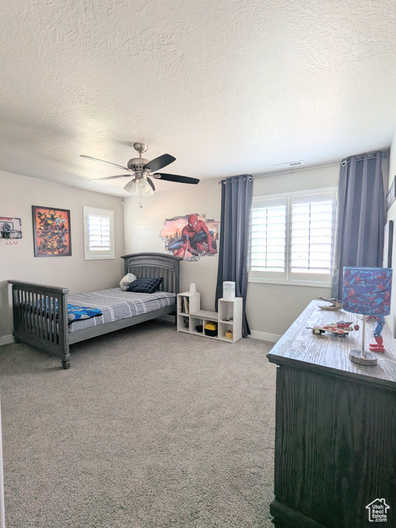 Carpeted bedroom with a textured ceiling and a ceiling fan