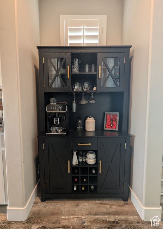Indoor dry bar with wood finished floors and baseboards