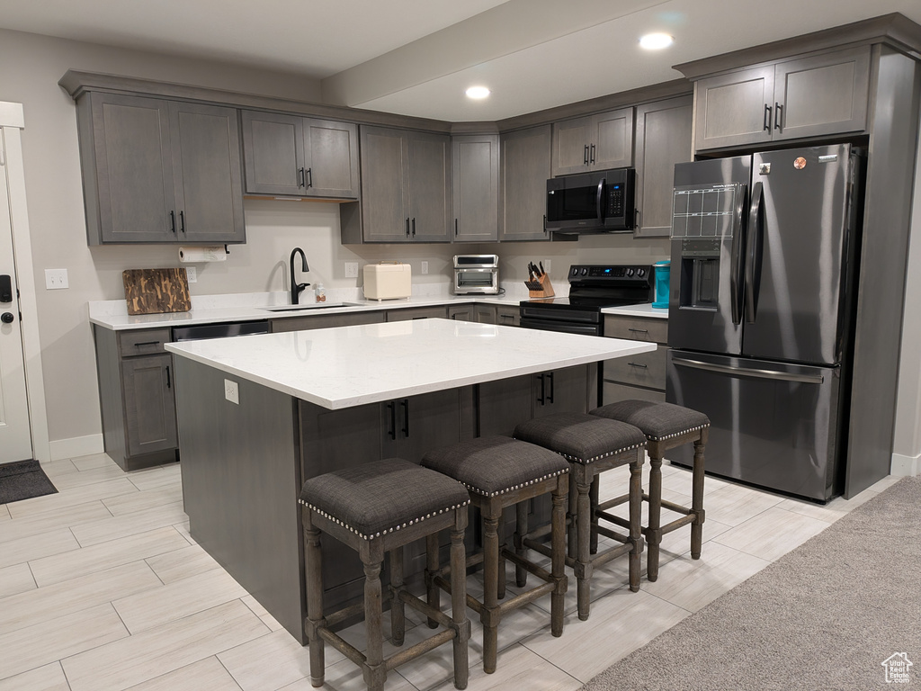 Kitchen with stainless steel appliances, a kitchen bar, a center island, light countertops, and recessed lighting