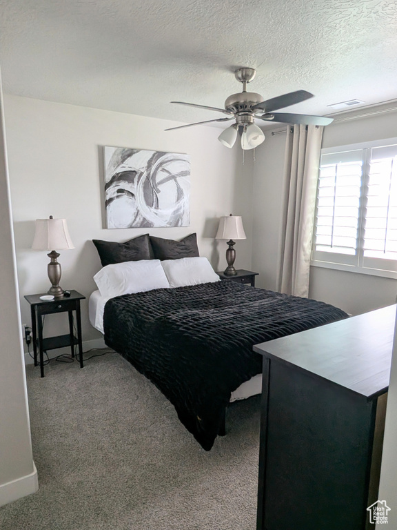 Carpeted bedroom with ceiling fan and a textured ceiling