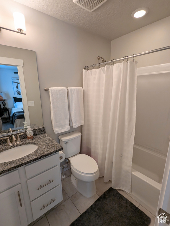 Bathroom with vanity, shower / tub combo, connected bathroom, a textured ceiling, and tile patterned flooring