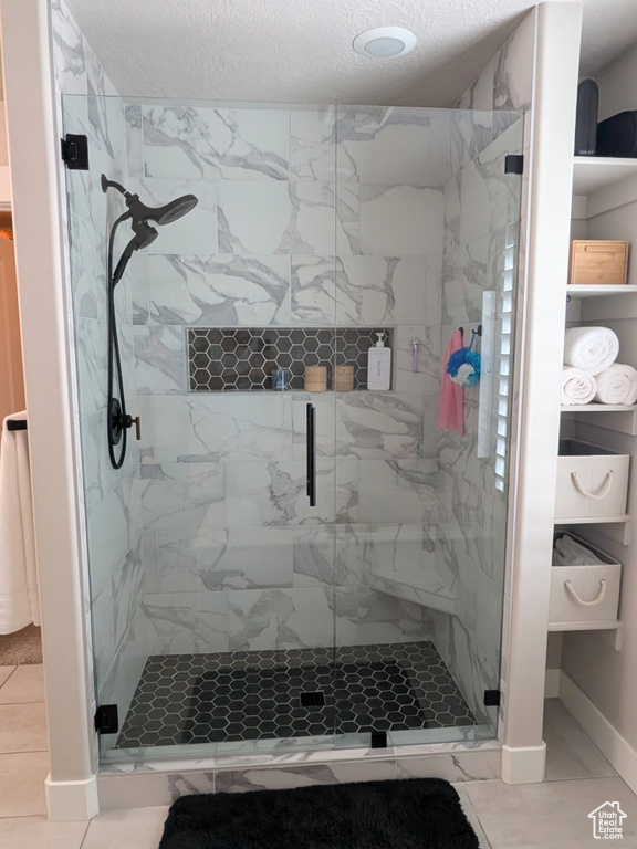 Full bath featuring a marble finish shower and a textured ceiling