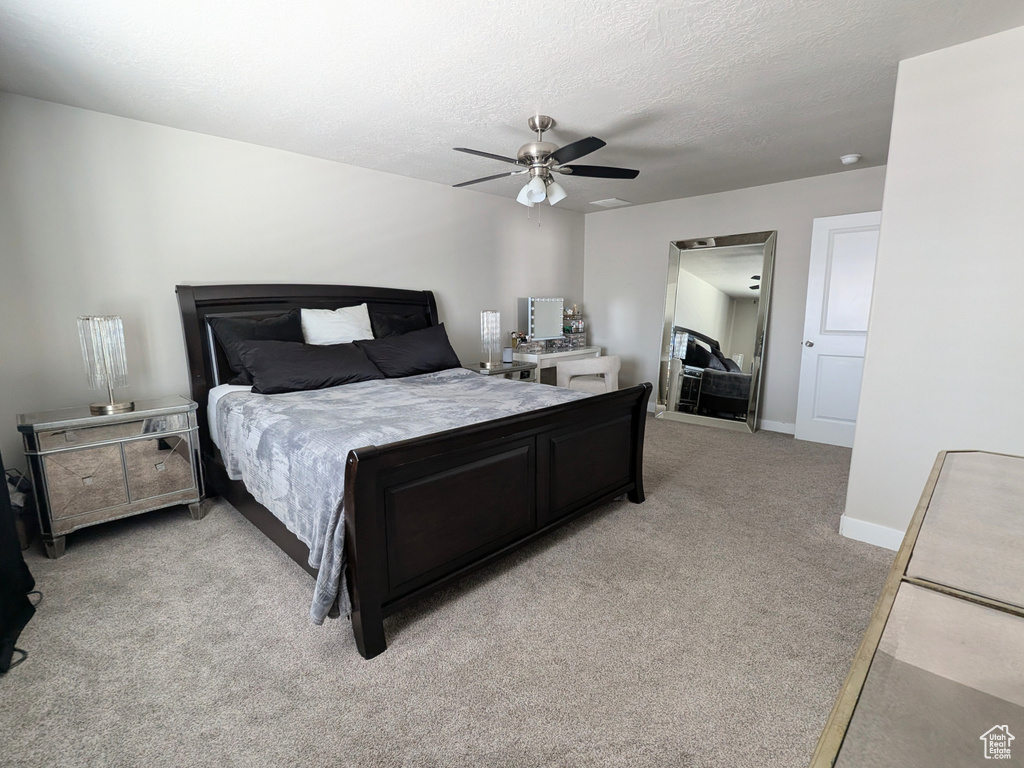 Bedroom with light colored carpet, a textured ceiling, and ceiling fan