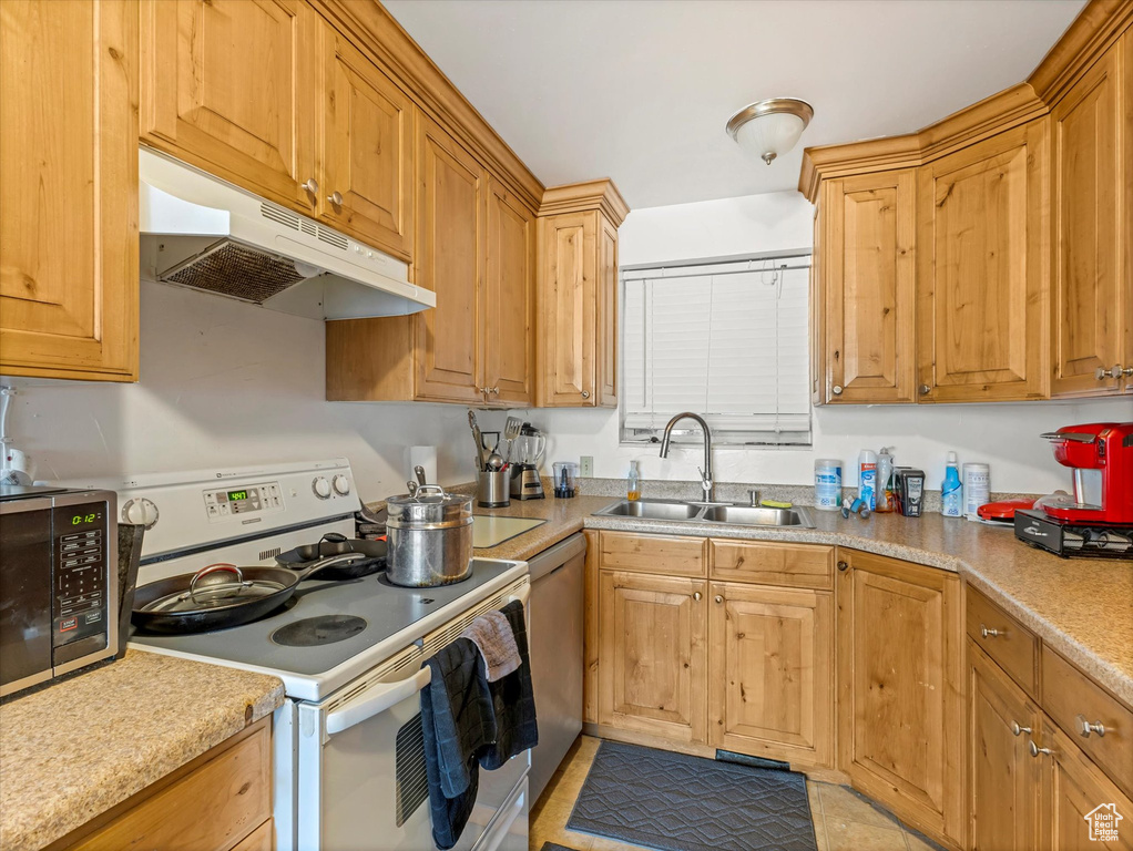Kitchen with stainless steel appliances, under cabinet range hood, and light countertops