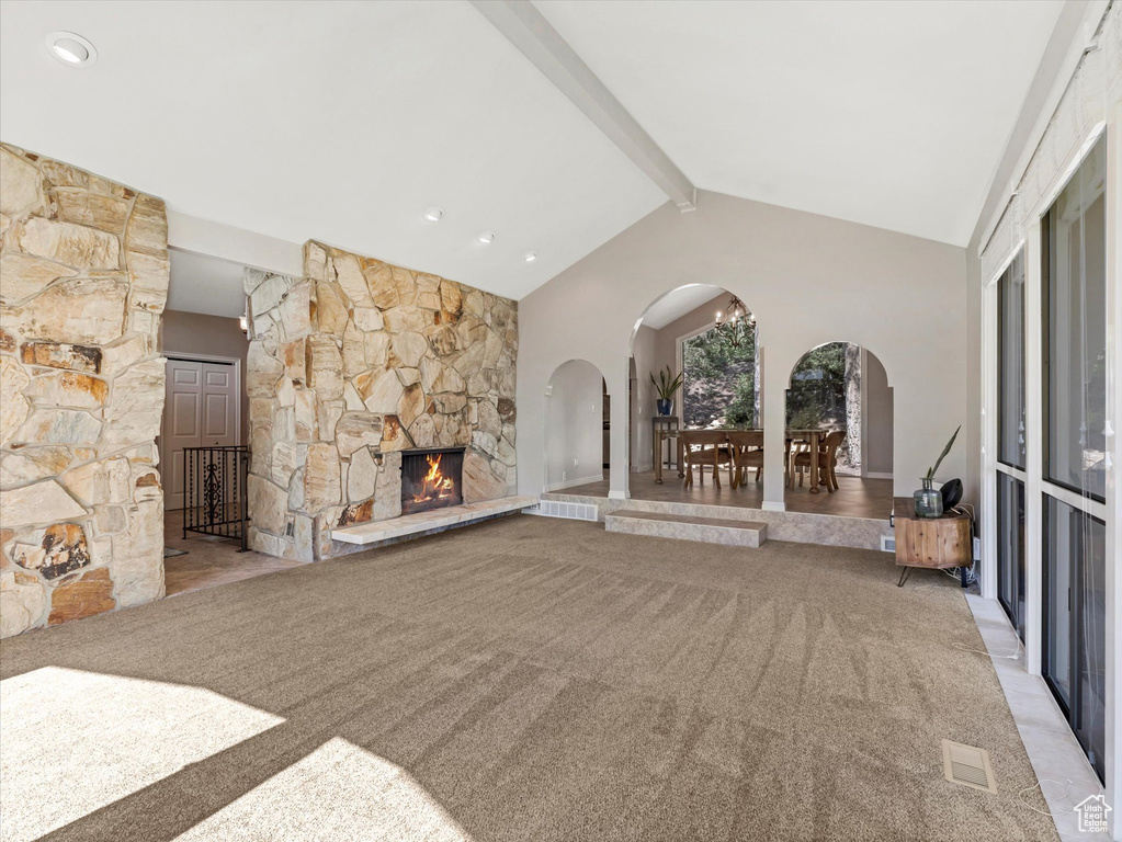 Unfurnished living room featuring arched walkways, carpet, and a fireplace