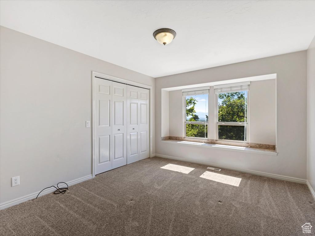 Unfurnished bedroom with carpet and a closet