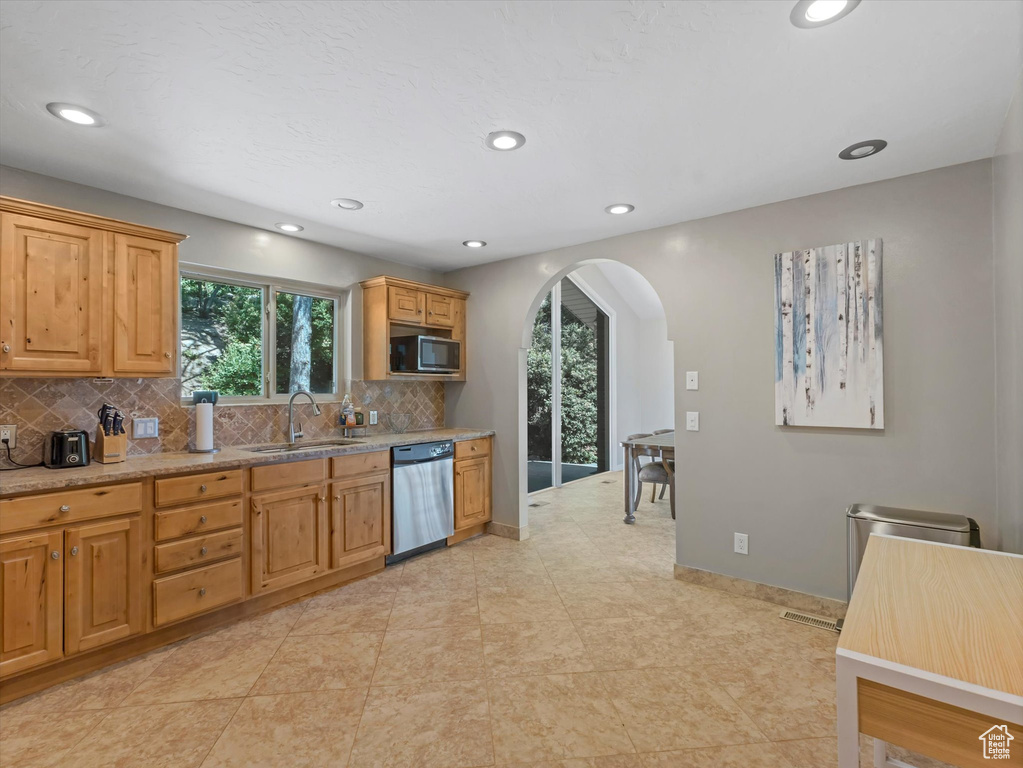 Kitchen featuring dishwasher, arched walkways, healthy amount of natural light, backsplash, and recessed lighting
