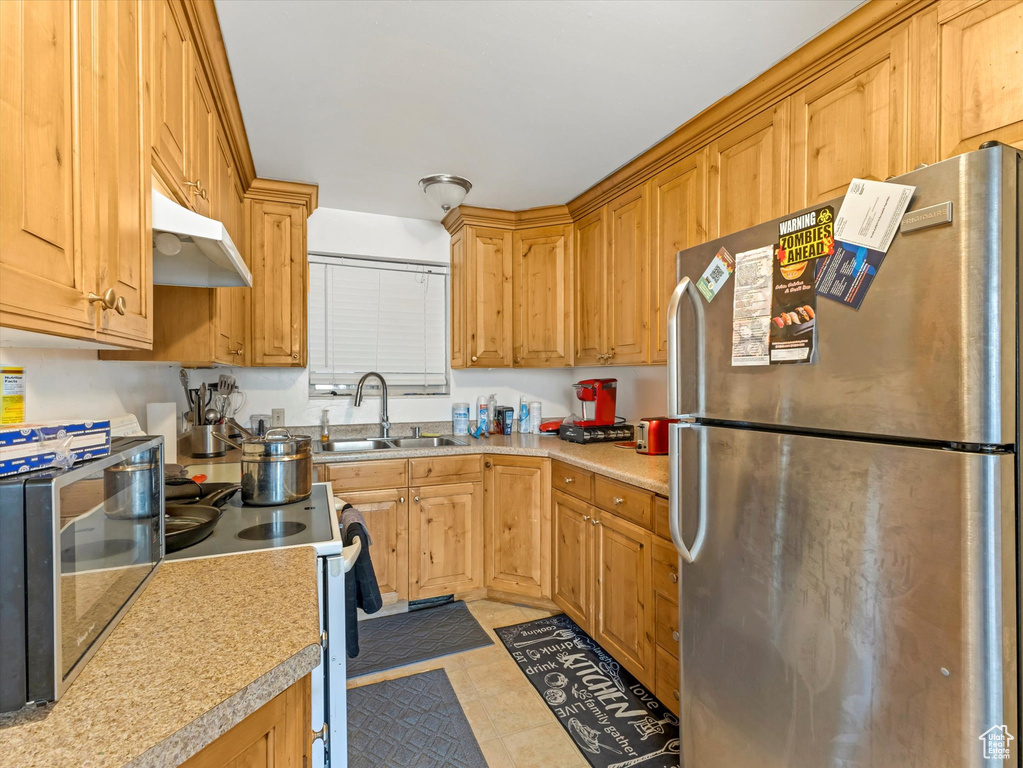 Kitchen featuring freestanding refrigerator, under cabinet range hood, light countertops, and white range with electric stovetop