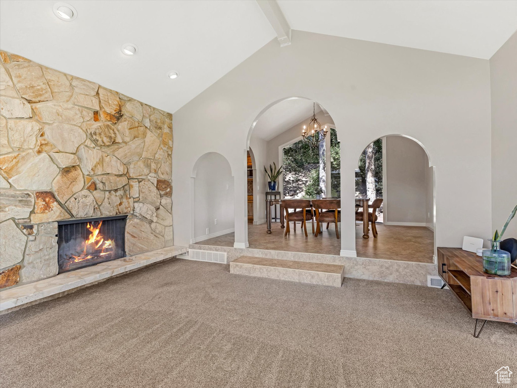Living area featuring arched walkways, carpet floors, a fireplace, beam ceiling, and high vaulted ceiling