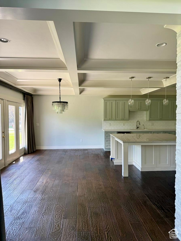 Kitchen with green cabinets, beam ceiling, dark wood-style floors, a kitchen bar, and backsplash