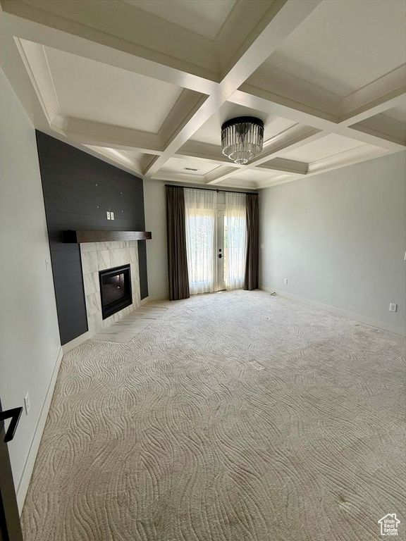 Unfurnished living room with coffered ceiling, french doors, carpet, a fireplace, and beamed ceiling