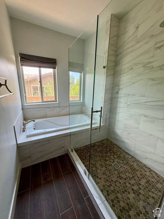 Full bath featuring a garden tub, a shower stall, and wood finished floors