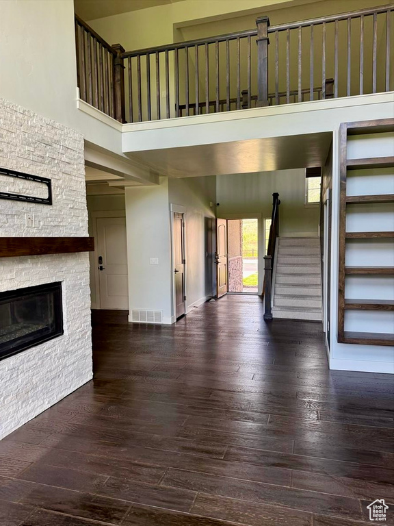 Unfurnished living room with a towering ceiling, stairway, a fireplace, and hardwood / wood-style flooring