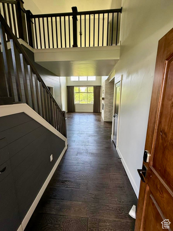 Hallway with stairway, dark wood-style flooring, and a high ceiling