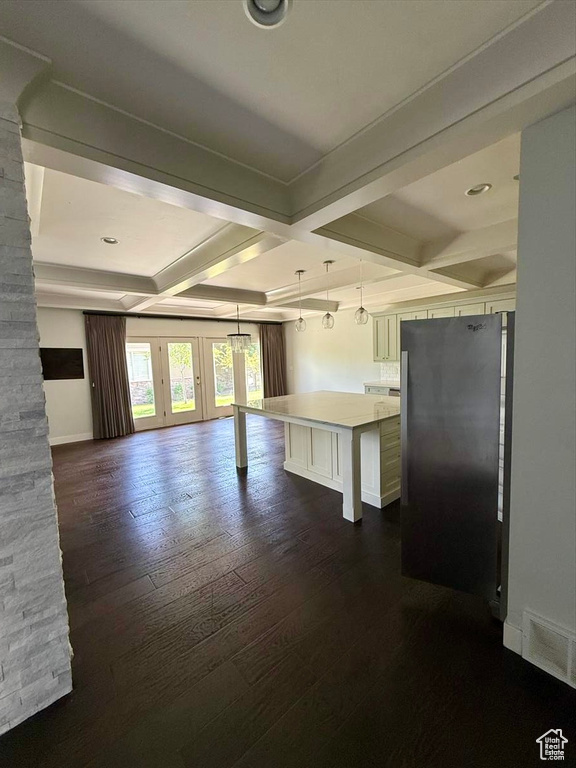 Kitchen with freestanding refrigerator, coffered ceiling, a kitchen breakfast bar, open floor plan, and dark wood-style flooring