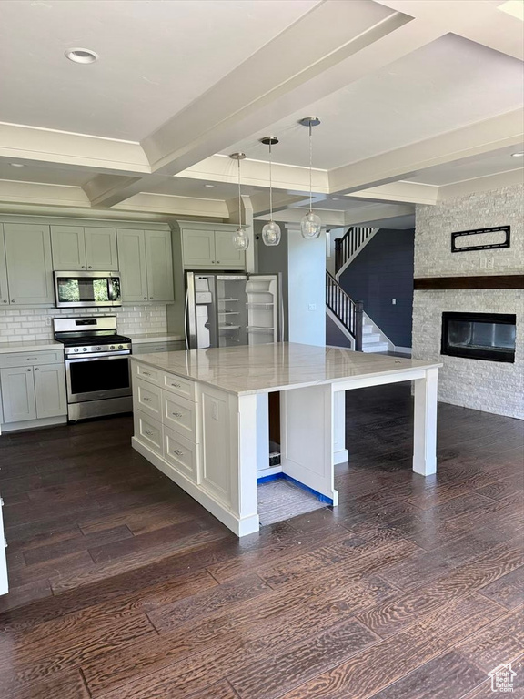 Kitchen featuring appliances with stainless steel finishes, dark wood finished floors, tasteful backsplash, decorative light fixtures, and beam ceiling