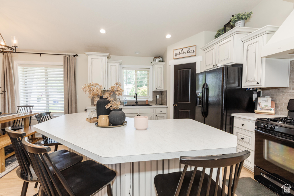 Kitchen featuring black appliances, a kitchen breakfast bar, backsplash, custom range hood, and recessed lighting