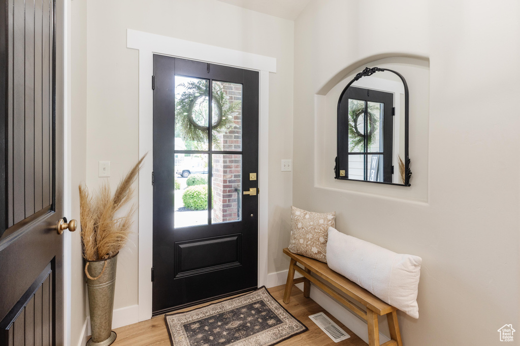 Foyer featuring healthy amount of natural light, light wood-type flooring, and arched walkways