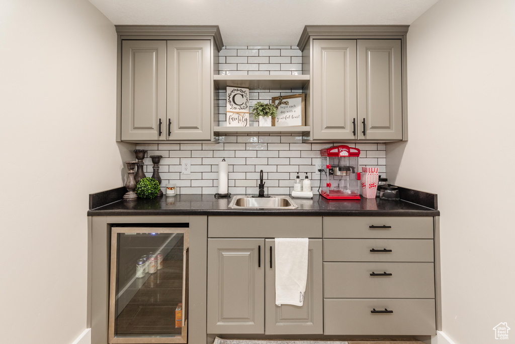 Indoor wet bar featuring wine cooler and decorative backsplash