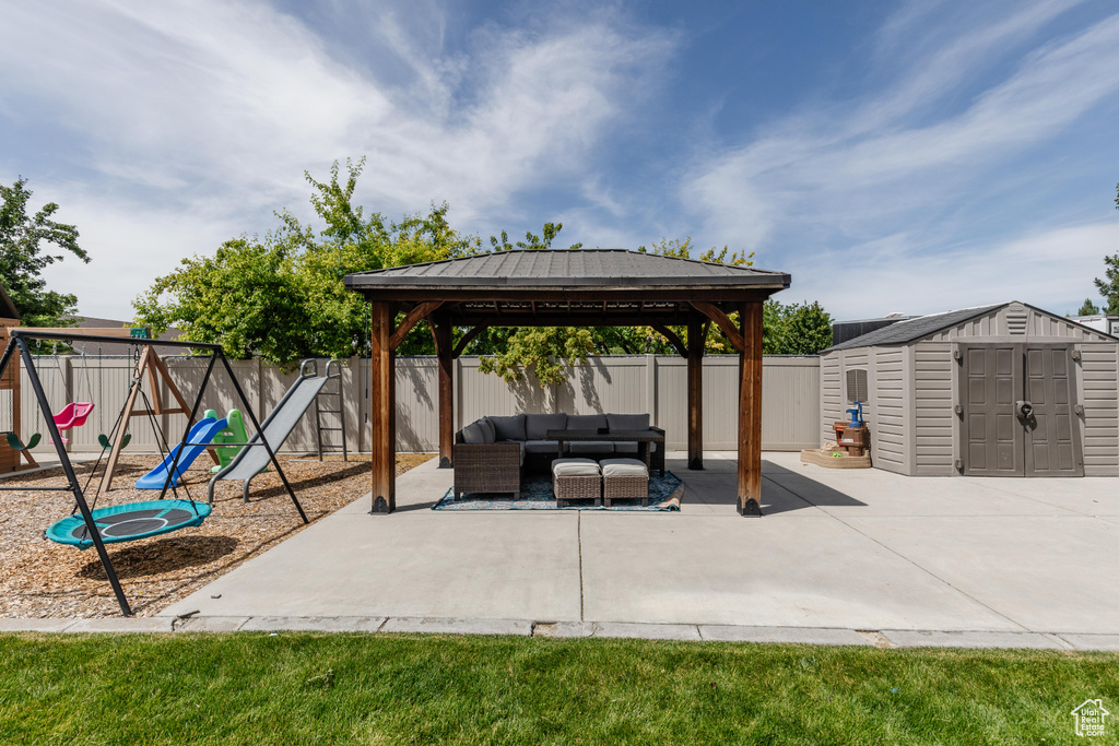 Fenced backyard featuring outdoor lounge area, a playground, a gazebo, a patio, and a storage shed