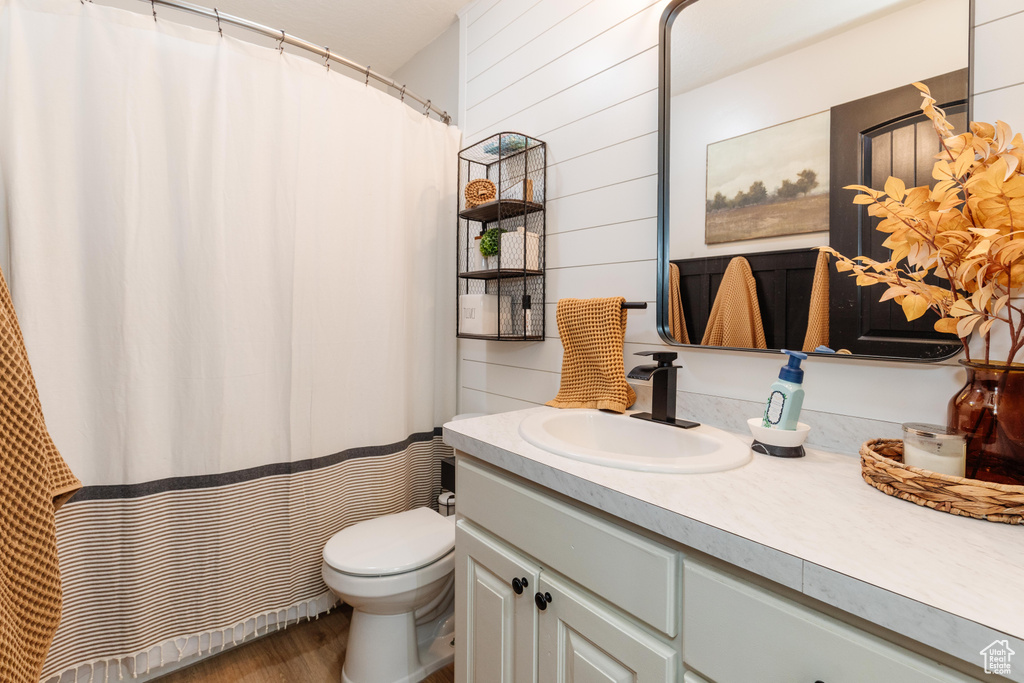 Full bath featuring vanity, wood finished floors, wood walls, and a shower with shower curtain
