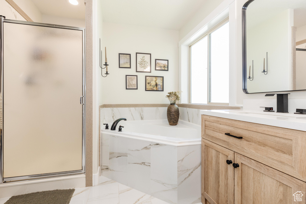 Bathroom featuring vanity, a stall shower, a bath, and marble finish floors