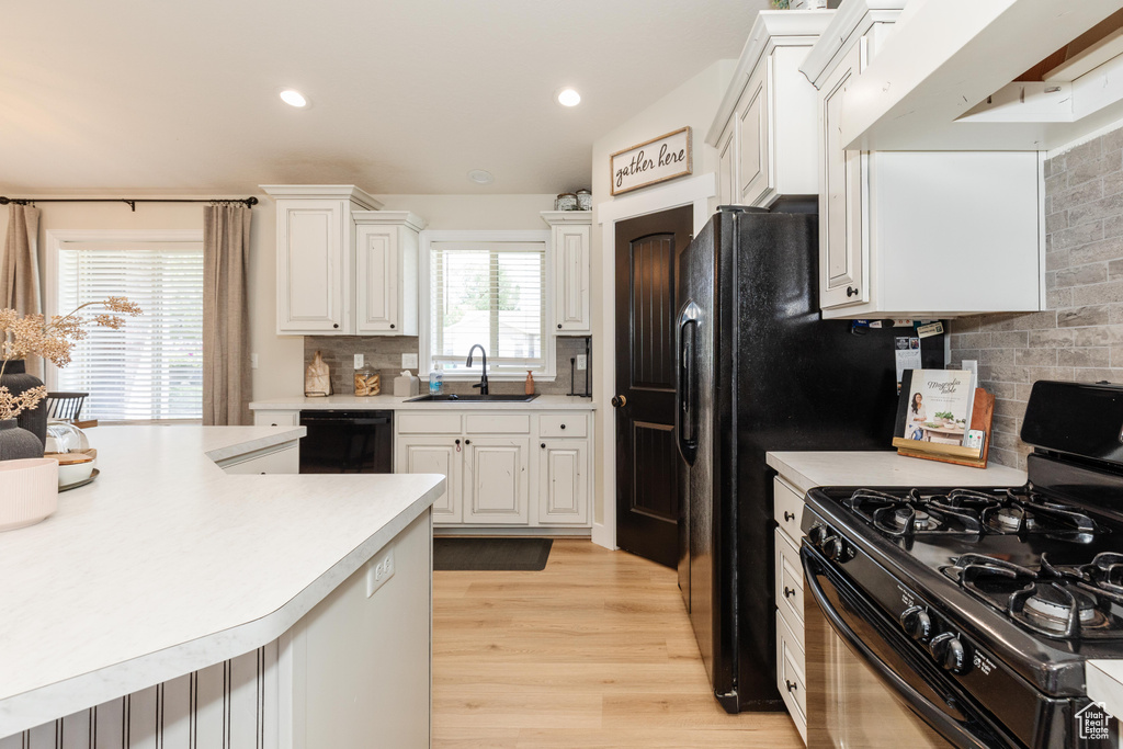 Kitchen featuring gas range, dishwasher, light countertops, light wood-type flooring, and recessed lighting