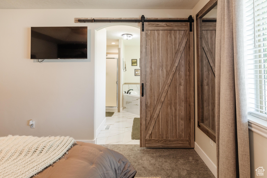 Bedroom with arched walkways, a barn door, and ensuite bath