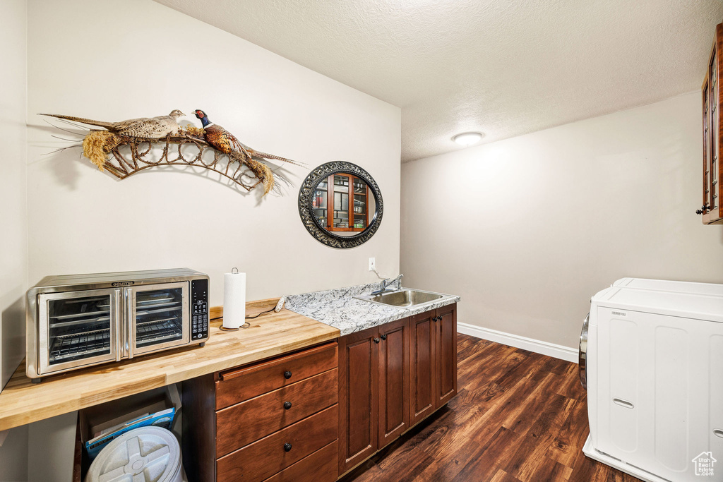 Bar featuring dark wood-style floors, independent washer and dryer, and a textured ceiling