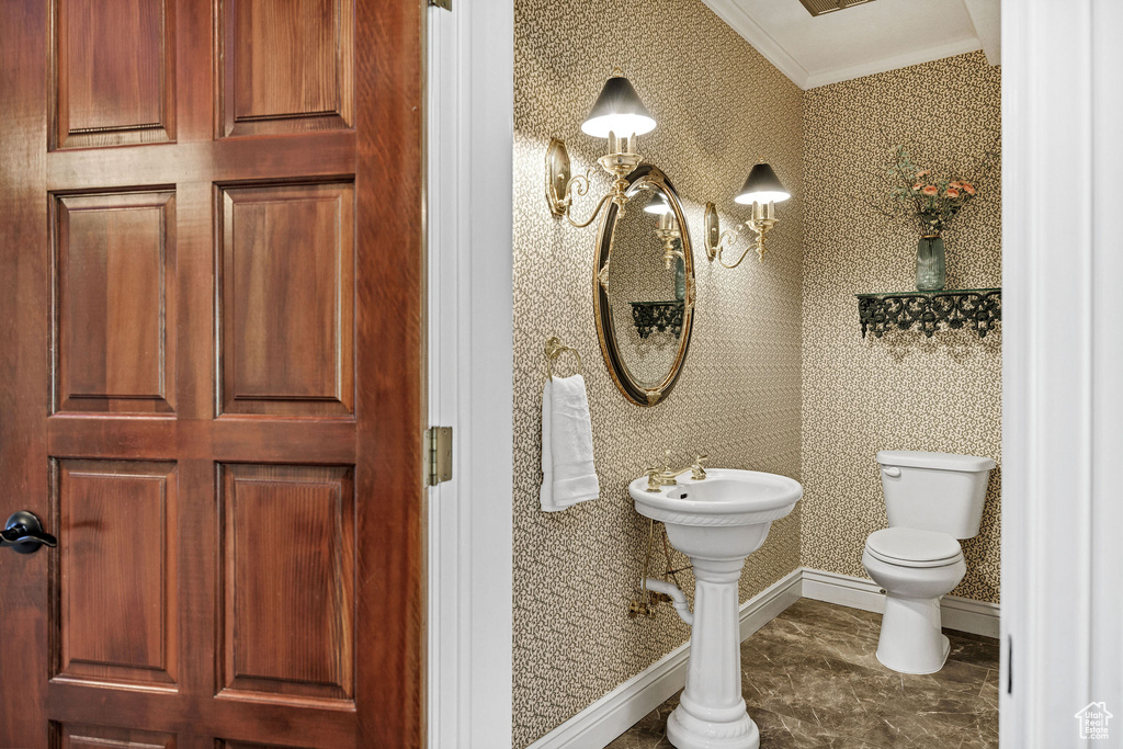 Half bath featuring ornamental molding and wallpapered walls