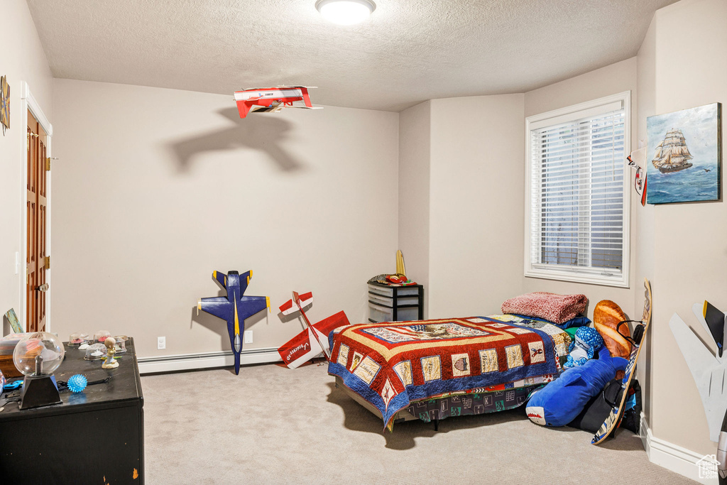 Bedroom with baseboard heating, carpet, and a textured ceiling